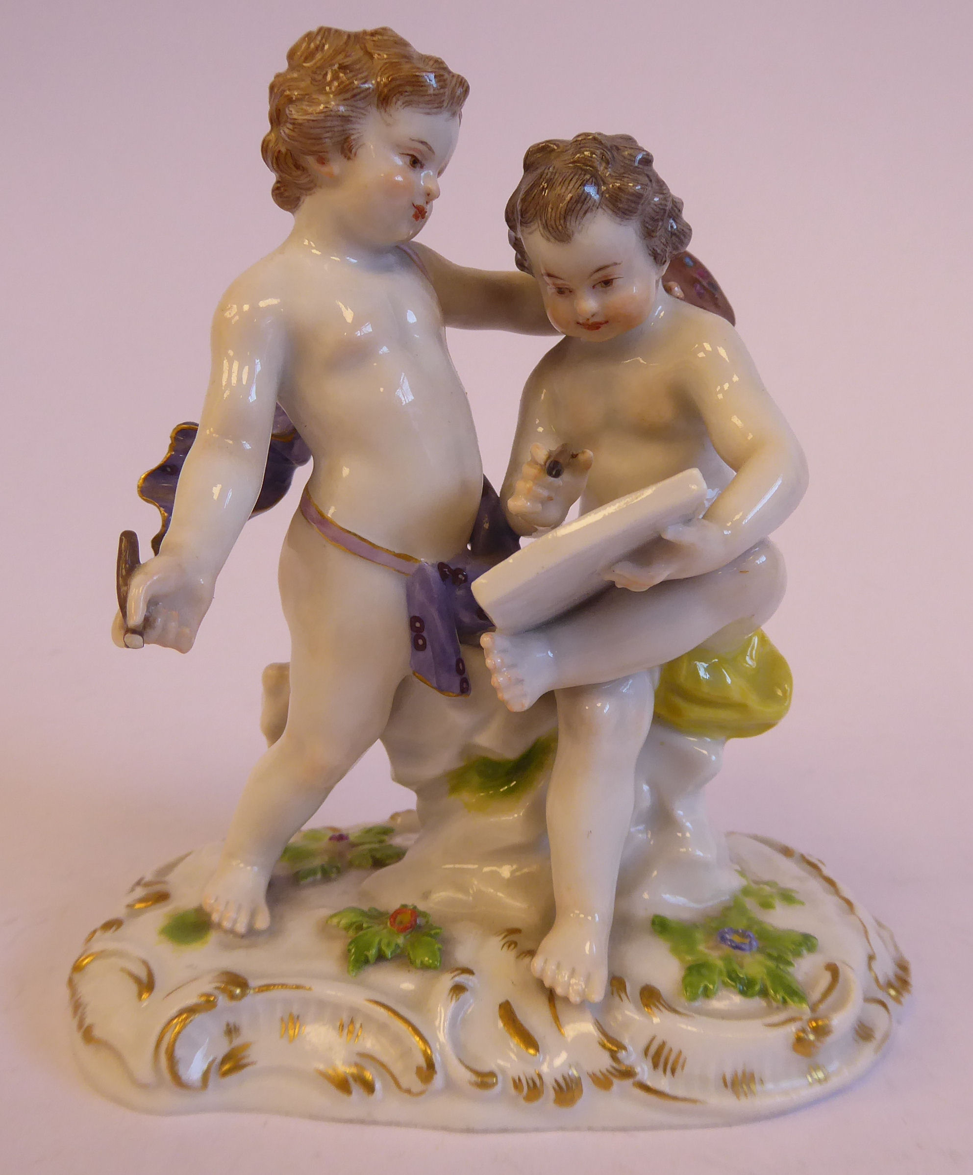 An early 20thC Meissen porcelain group, featuring two cherubic figures with an artist's board (No.