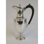 A late Victorian silver hot water jug of shouldered pedestal vase design with a waisted neck,