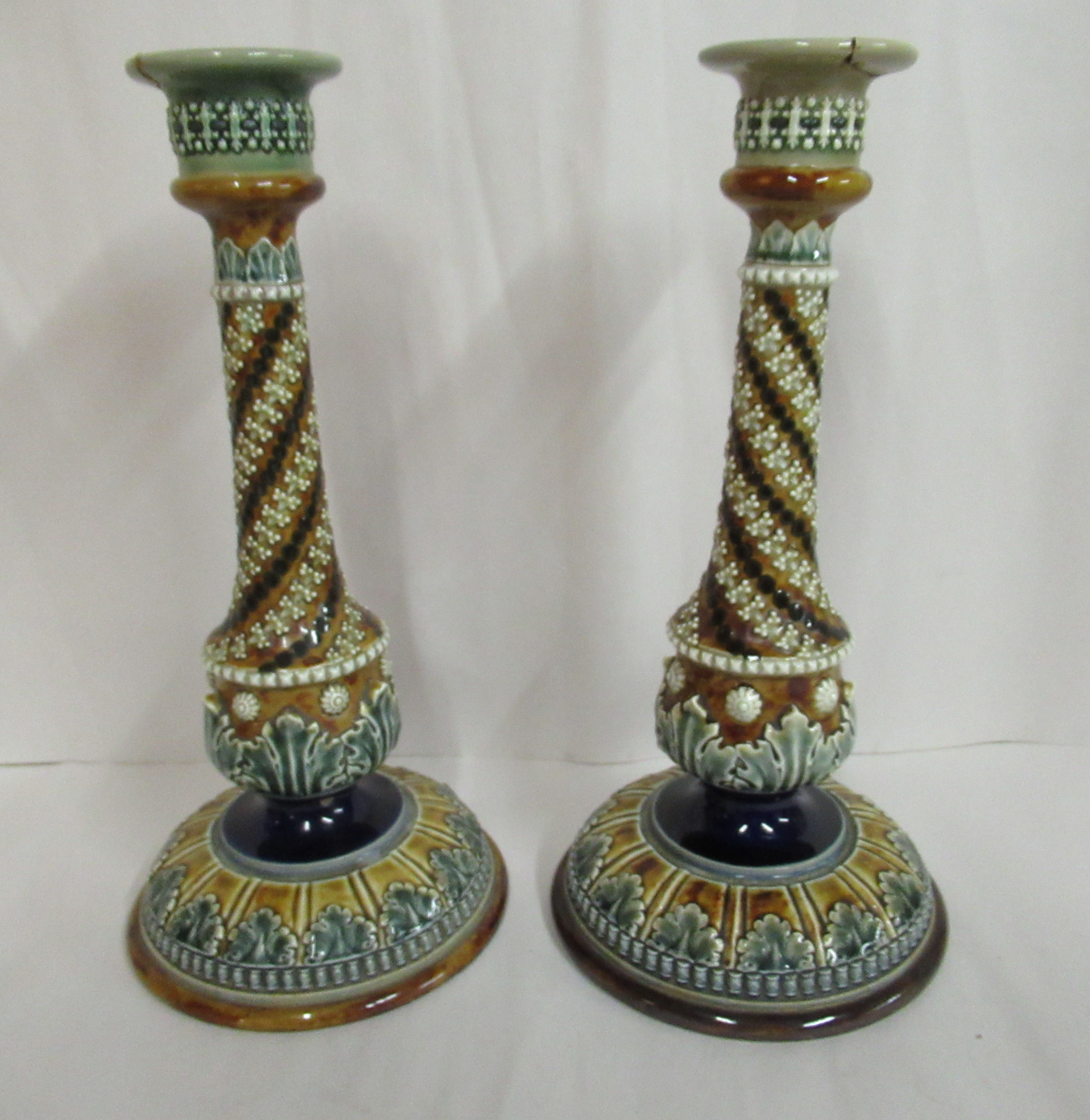 A pair of Doulton Lambeth blue, green and brown glazed stoneware candlesticks, decorated in moulded,