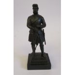 A late 19thC cast and patinated iron figure, a standing highland soldier,