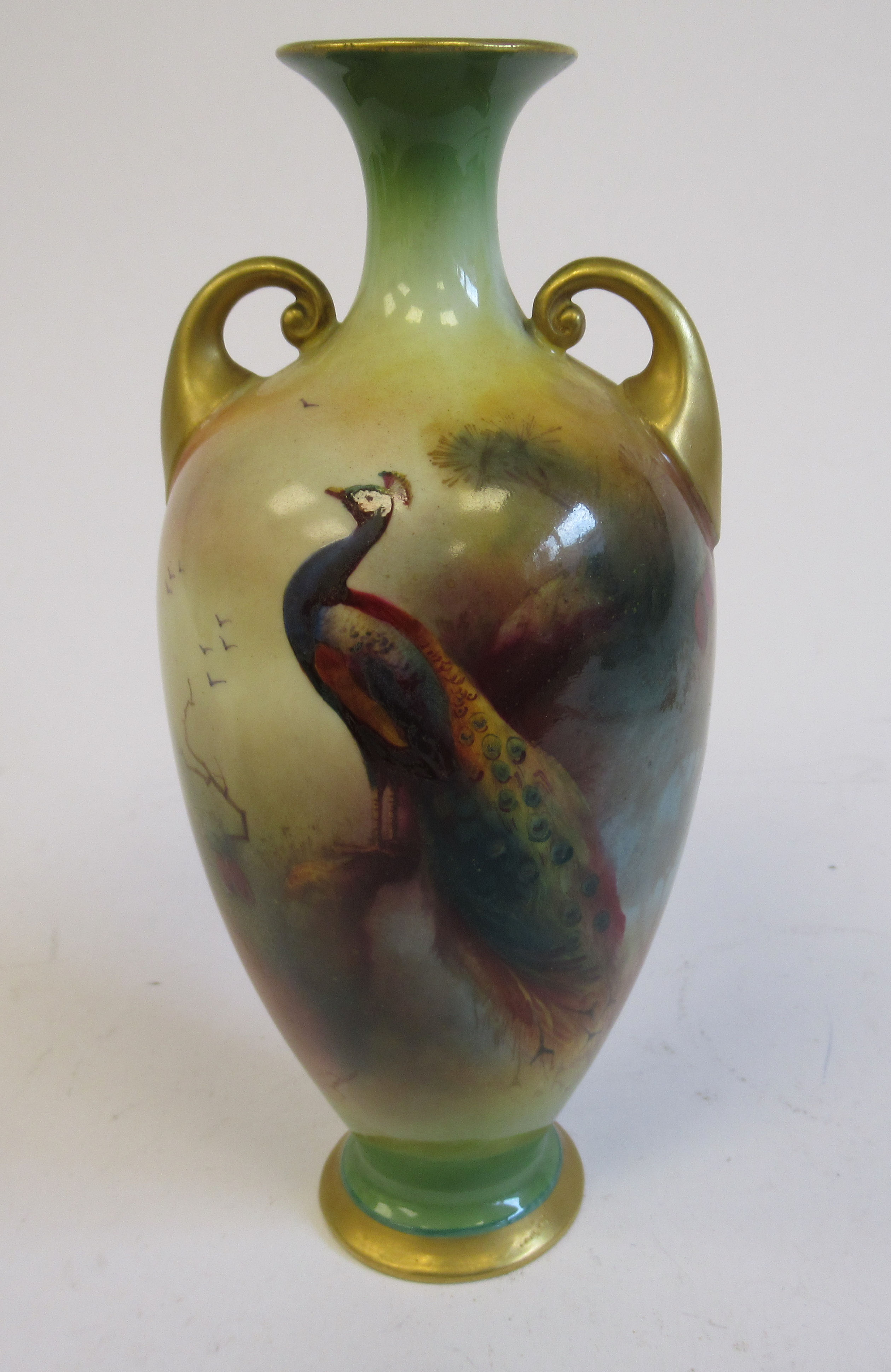 A Royal Worcester china pedestal vase of ovoid form, having a narrow neck, flared rim and twin,