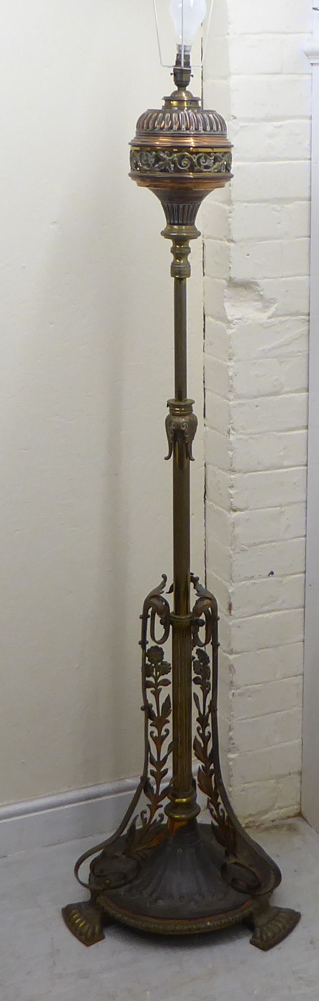 A late Victorian copper and brass lamp standard with a reservoir, over a height adjustable column,