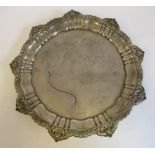 An Edwardian silver salver with a raised gadrooned and shell cast border,