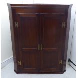 A 19thC panelled oak hanging corner cupboard with brass fittings,
