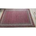 A Persian rug, decorated with repeating small trees, bordered by stylised foliate designs,