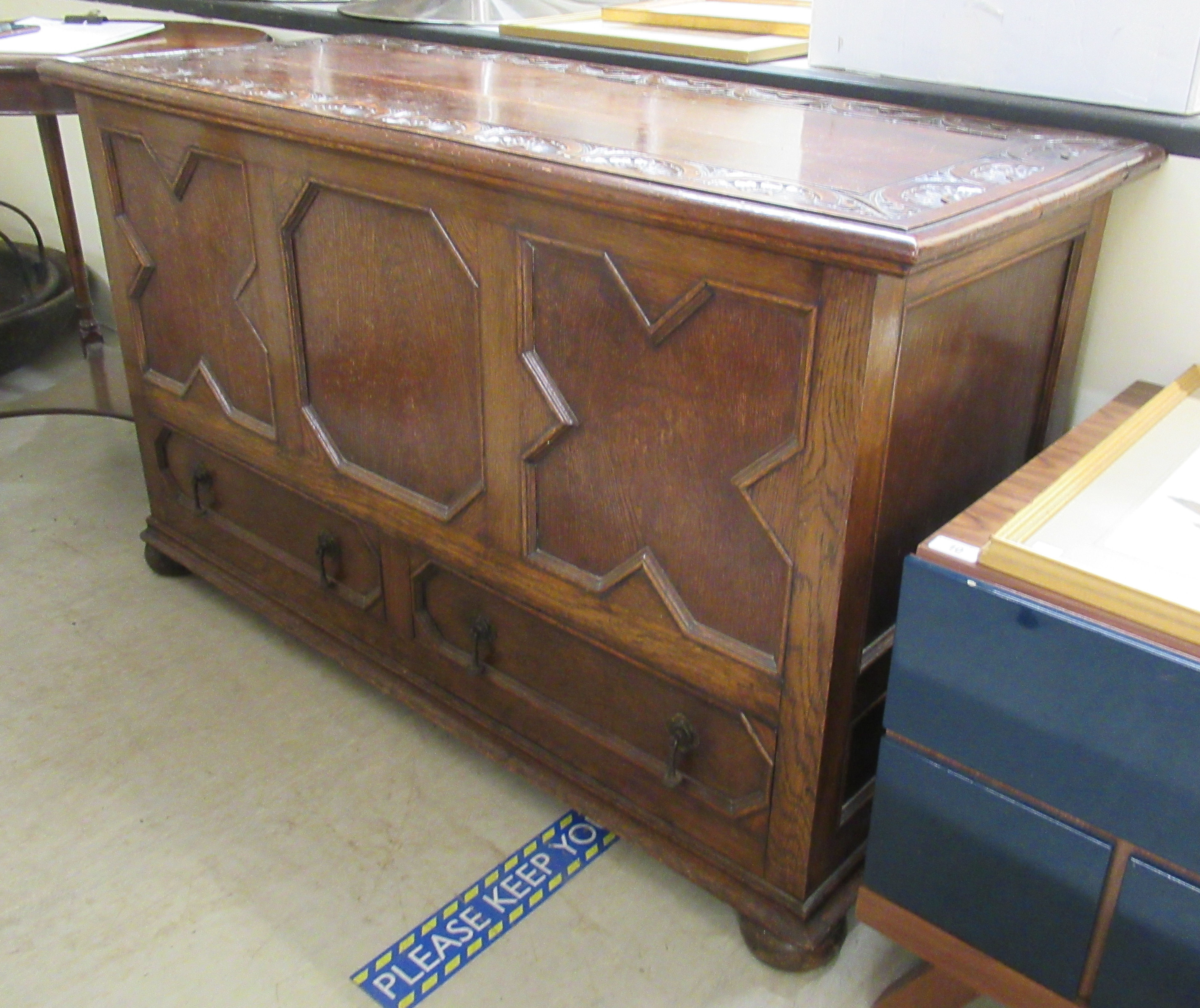 A 1930s oak mule chest with a hinged lid, over a tri-panelled front and two base drawers,