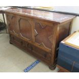 A 1930s oak mule chest with a hinged lid, over a tri-panelled front and two base drawers,