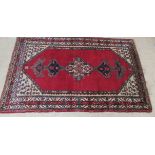 A Persian rug, decorated with stylised designs,