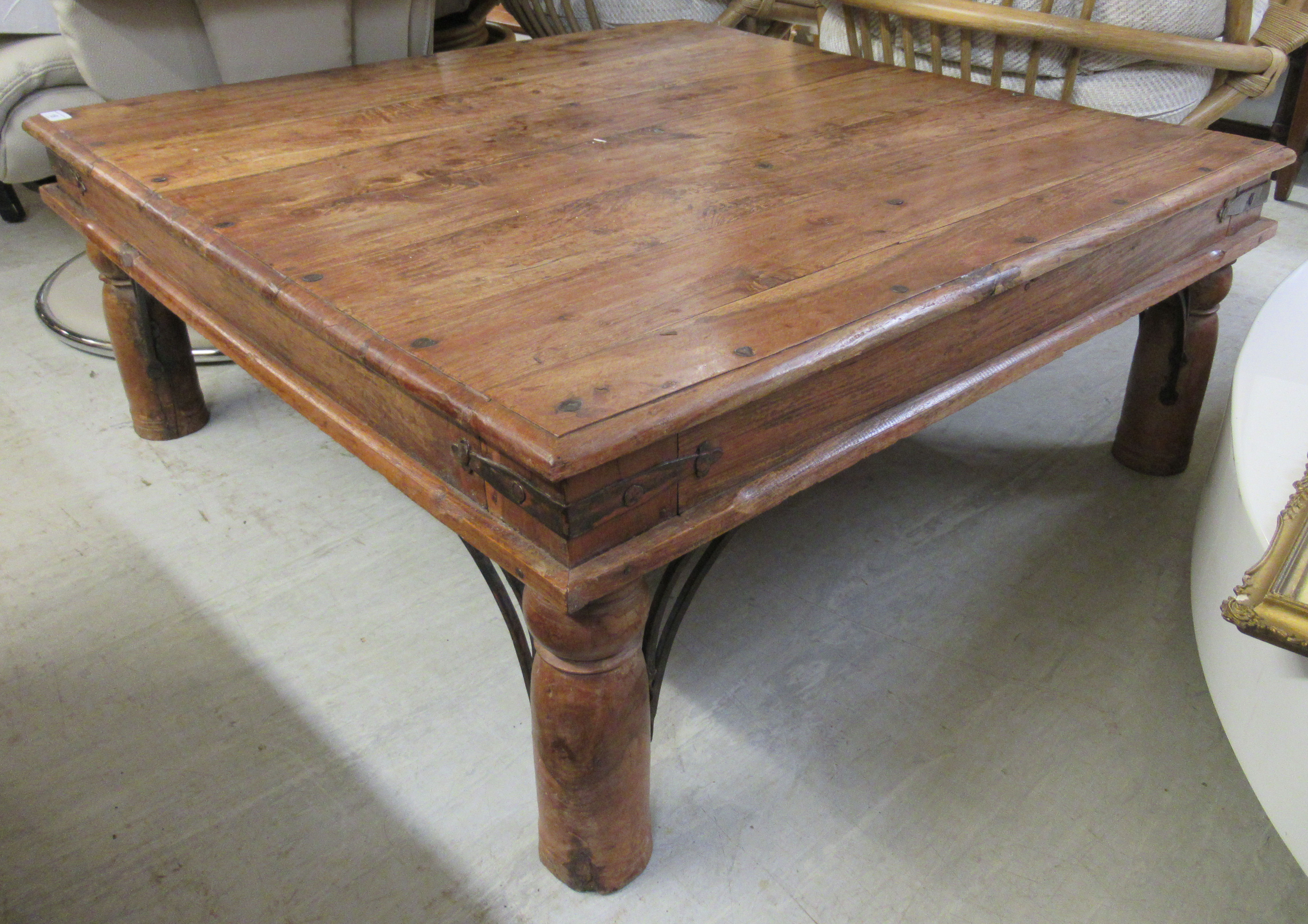 A modern Indonesian teak coffee table, raised on turned legs and wrought iron bracket supports 15.