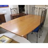A modern cherrywood dining table, the top with elliptical sides,