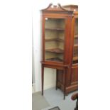 An Edwardian mahogany corner cabinet with a glazed door, enclosing three open shelves,