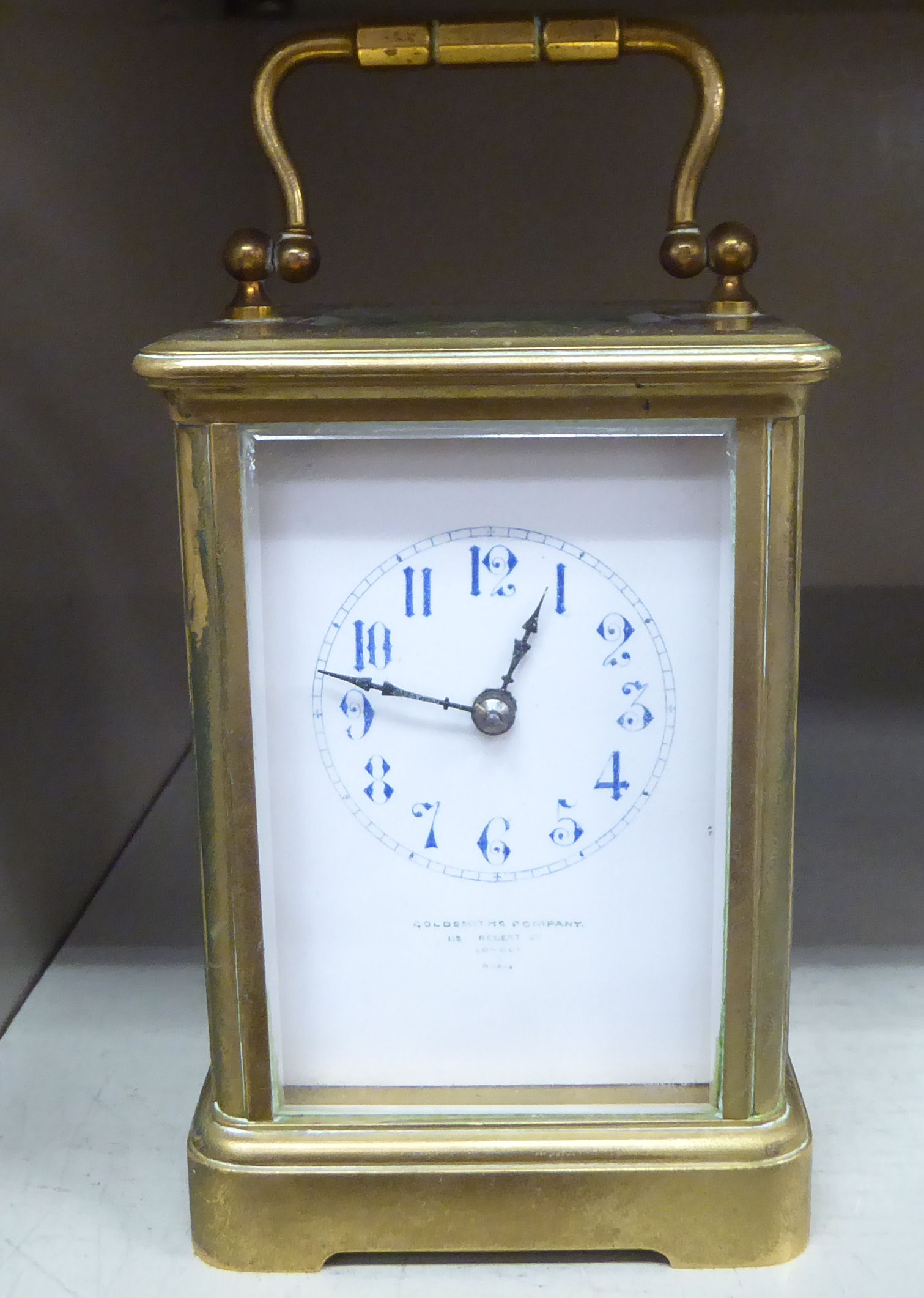 An early 20thC lacquered brass cased carriage timepiece with bevelled glass panels and a folding