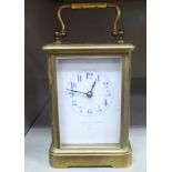 An early 20thC lacquered brass cased carriage timepiece with bevelled glass panels and a folding