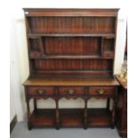 A 20thC Old English style stained oak dresser, the superstructure with two open shelves,