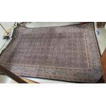 A Persian rug, decorated with repeating flowerhead motifs, bordered by other stylised designs,