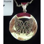 A silver disc design pendant locket, decorated with a butterfly,