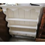 A modern white painted hanging plate rack with three open shelves,