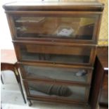 A 1920s Globe Wernicke oak four tier bookcase, enclosed by glazed rise-and-slide doors,