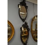 A pair of 20th century oak blackforrest style oval mirrors, the oval plates contained within moulded