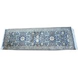 Silk Kashmieri rug, with floral scrolls on a blue ground, 62 x 195cms.
