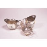 Two silver jugs and a tea strainer on stand