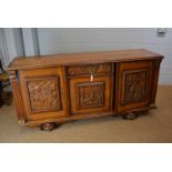 A 20th Century carved oak sideboard, fitted a single drawer and cupboards, each cupboard decorated