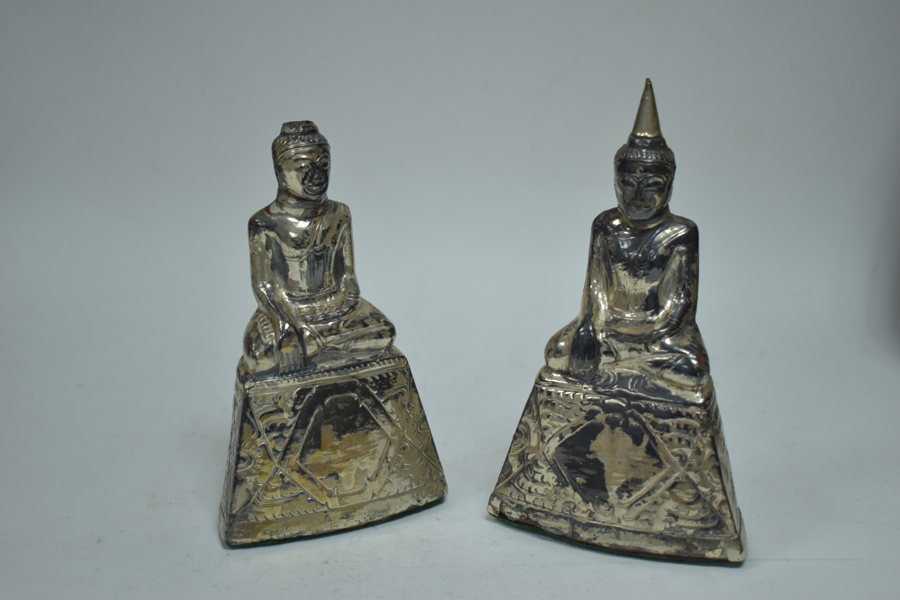 A pair of white metal mounted buddha statues