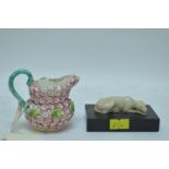 carved stone dog on plinth; and flower encrusted jug.