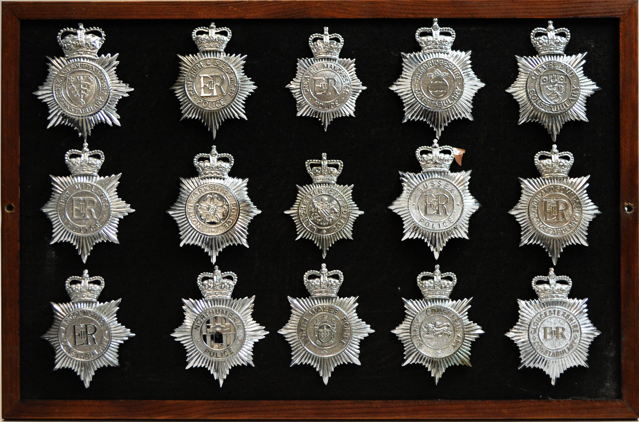 A collection of 20th Century Police helmet badges, framed.