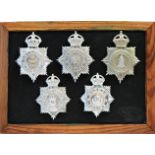 A collection of 20th Century Police helmet badges, framed.