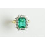 An emerald and diamond cluster ring