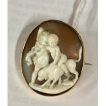 An oval shell cameo brooch carved with two putti seated on a hound