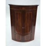 A George III inlaid mahogany bowfront hanging corner cupboard