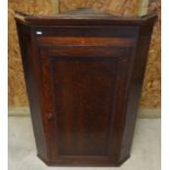 A Georgian oak hanging corner cupboard with single panelled door enclosing three shelves