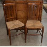 A pair of Arts and Crafts oak side chairs with rush seats and heart shaped motifs a/f