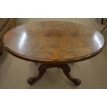 A Victorian oval tilt top breakfast table with burr walnut top raised on heavily carved quad base