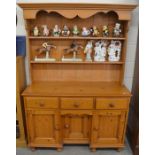 A pine kitchen dresser, the plate rack with two shelves on a base with three drawers and panelled