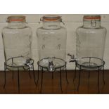 A set of three large kilner jars with taps on metal stands