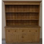 A large stripped pine kitchen dresser, the plate rack with two open shelves on a base with three