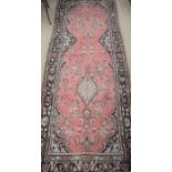 A Persian Hamadan runner, the stylised floral design on red ground within a dark palmette border,