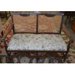 A carved oak and cane worked two seater settle with floral upholstery with exotic birds