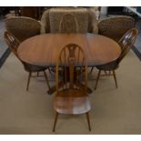 An Ercol dark elm extending dining table, the oval top with 'butterfly' folding central leaf to/w