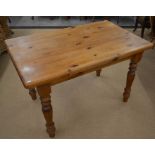 A waxed pine kitchen dining table with rounded rectangular top raised on turned supports