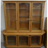 A modern light oak two section display cabinet with six glazed doors enclosing adjustable