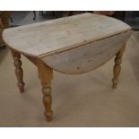 An antique stripped pine drop leaf kitchen dining table on turned supports