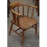 An early 20th century elm seated bow chair raised on turned supports with stretchers