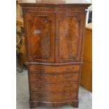A mahogany serpentine front cabinet with panelled doors as a central drawer and cupboard door raised