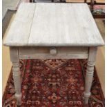 An antique stripped pine kitchen dining table with frieze drawer, raised on turned supports
