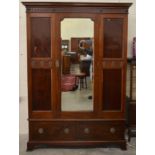 An Edwardian mahogany wardrobe, the central mirrored door above two base drawers with ring pull