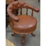 A mahogany turned spindle back bow chair with tan leather upholstery, circular seat and four